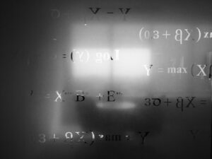 Un vetro opaco in una sala riunioni con delle equazioni matematiche scritte sopra.