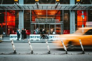 Ingresso dell'edificio del New York Times con strada davanti e machine che sfrecciano.