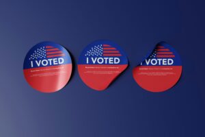 Immagine di 3 pallini tondi con scritta "I VOTED" a tema elezioni americane, su sfondo blu scuro.