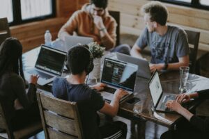 gruppo di 5 persone, a un tavolo di un bar, stanno lavorando al pc.