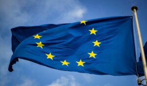 Bandiera europea che sventola al vendo con in sfondo un cielo azzurro con qualche nuvoletta leggera.