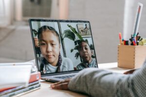 immagini di due bambini sullo schermo di un pc portatile come fossero in una videochiamata.