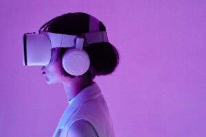 immagine di signora che indossa un visore 3D per la realtà virtuale. Sfondo rosa, poco illuminato.
