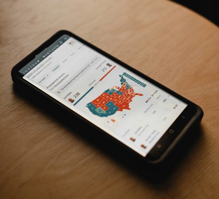 Immagine di una schermata cellulare aperta su una pagina che analizza le elezioni elettorali tra destra e sinistra negli USA: mappa con suddivisione colorata rosso-blu.
